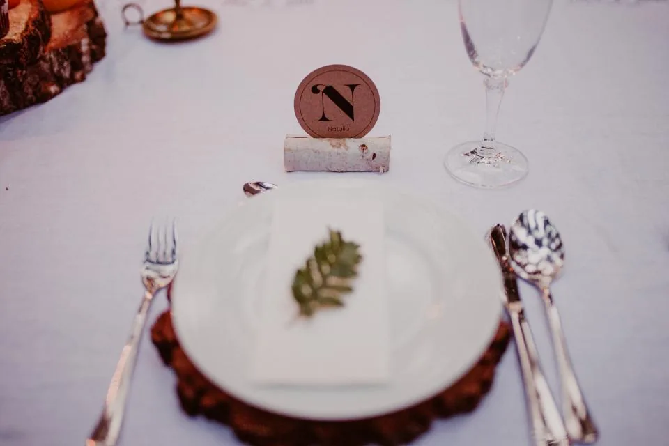 Cubierto preparado sobre mantel blanco con plato, copa y tarjeta de identificación de mesa