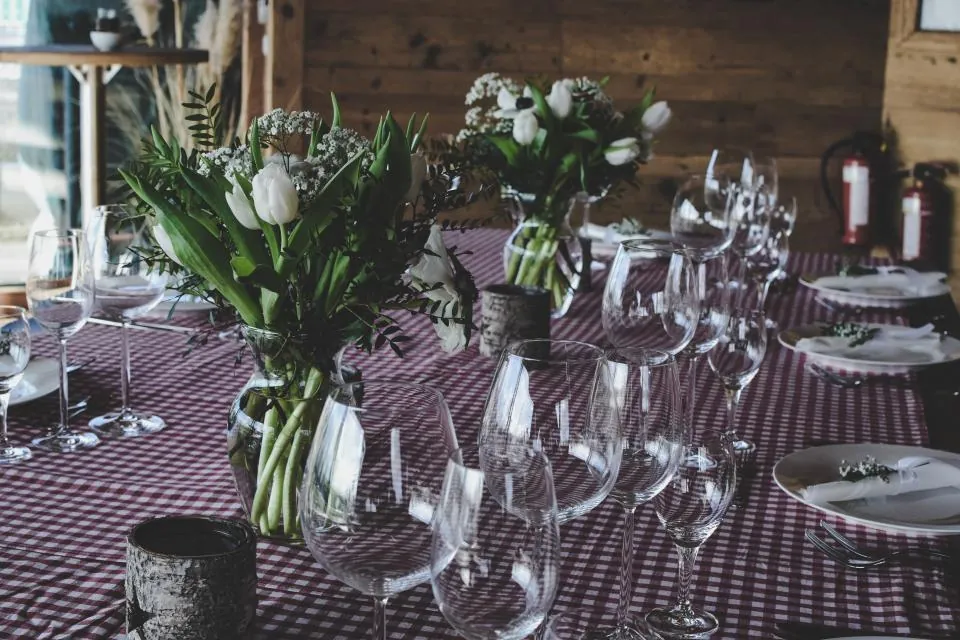 Mesa de evento armada con flores, copas y vajilla